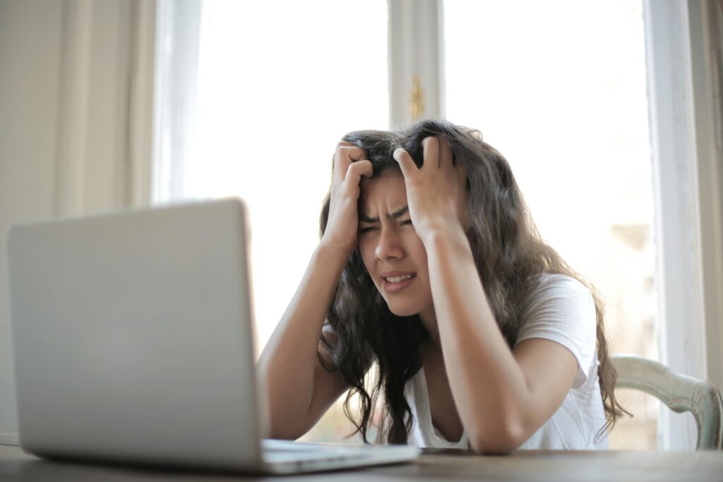 A frustrated business owner, a woman, looking at her laptop with a concerned expression.